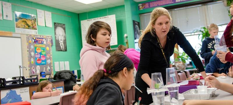 Teacher working with young students at a table.