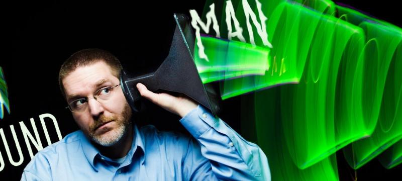 Andrew Barnard holding a funnel to his ear.