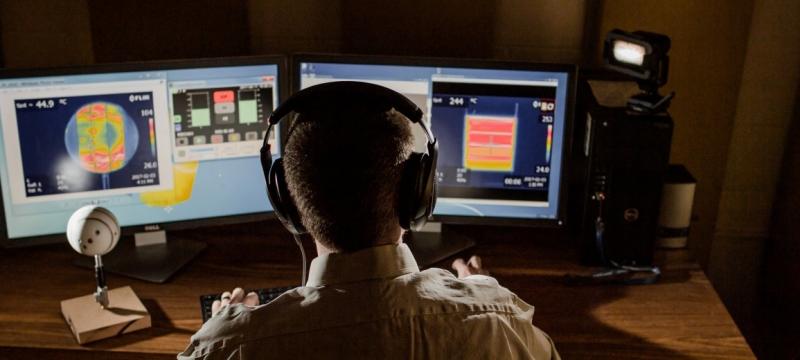 Person sitting at a computer with headphones on.