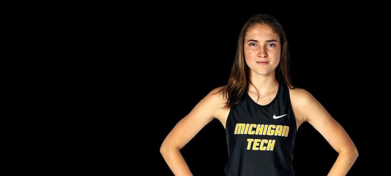 A runner in a Michigan Tech Jersey stands with hands on her hips. She just set a world record for crutch-running.