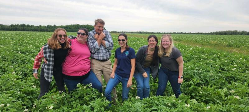 Allyson McQuiston and five co-workers laughing together in a potato field.