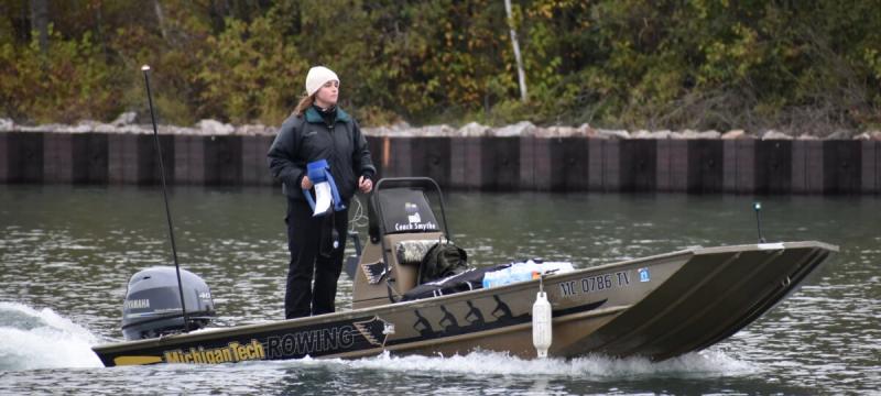 Megaphone in one hand, gearshift in the other, software engineering major Elise Buzzell keeps an eye on the Michigan Tech rowers from the coach boat. (Photo courtesy the Rowing Club at Michigan Tech)