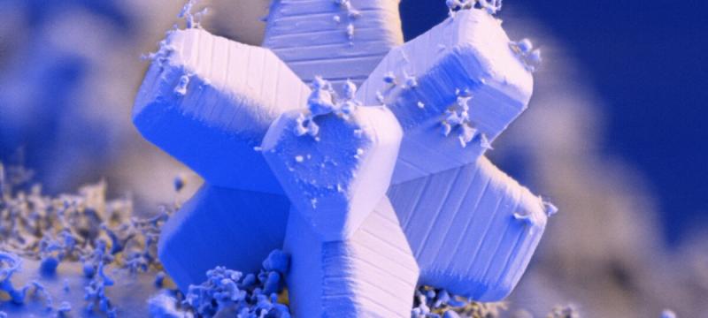 A microscopic image of a snowflake, featuring a unique geometric structure artificially colored blue, purple, and white.