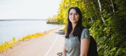 Jennifer Celeste stands with a backpack over her shoulder on a paved waterfront trail.