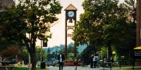 Students walk in front the Michigan Tech clock tower on campus at dawn