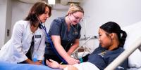 A nursing instructor works with two nursing students in the four-year program at Michigan Tech.