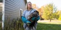 A Michigan Tech police sgt. who is also a raptor rehabilitator holds a bald eagle in her arms.