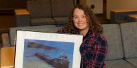 A first-year Tech student with a fascination for shipwrecks holds a print of the Edmund Fitzgerald