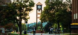 Students walk in front the Michigan Tech clock tower on campus at dawn