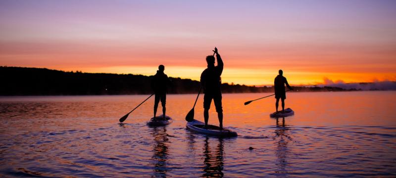Three people paddleboarding during a sunrise.