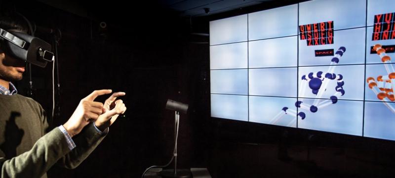 Person wearing VR goggles interacting with virtual keyboard.
