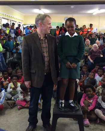 Michigan Tech Concert Choir Director Jared Anderson poses with a new friend during a visit to a South African school. The choir spent two weeks in South Africa in May.