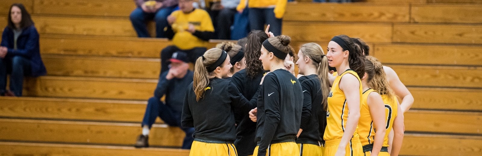 Michigan Technological University Women's Basketball Team huddles for a quick strategy session on the basketball court. 