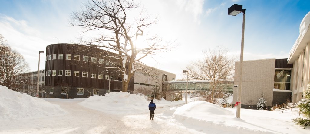 A single student walks Michigan Tech campus in winter.