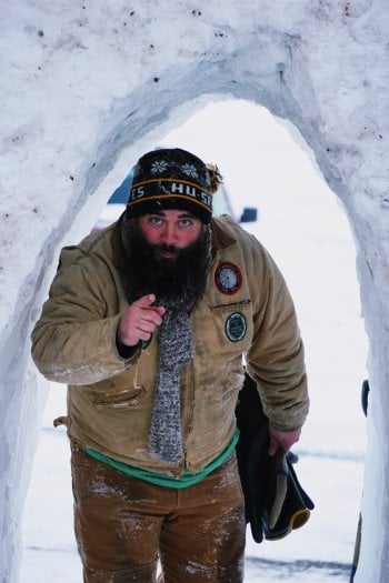 A man with cheeks red from the cold in a snow archh