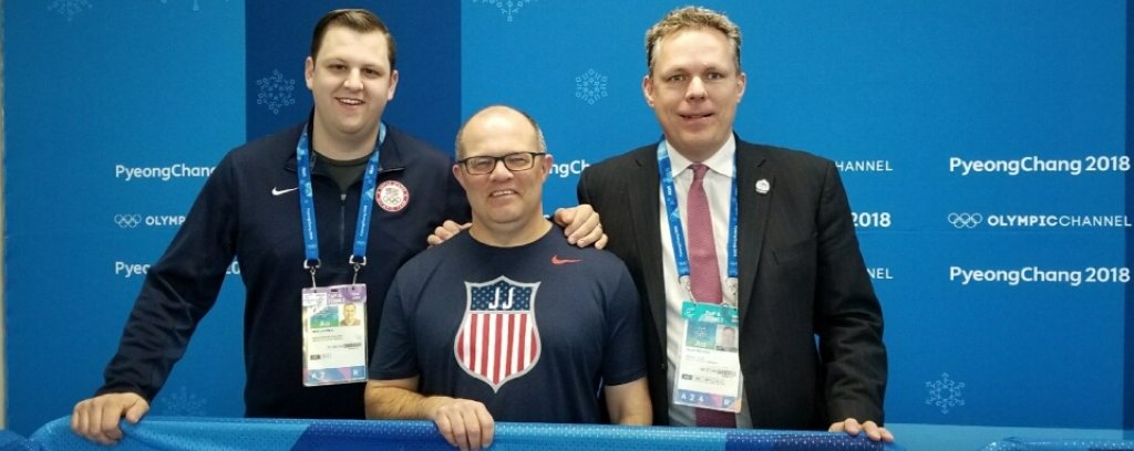 Three men stand smiling against a backdrop that reads PyeongChang and Olympics.