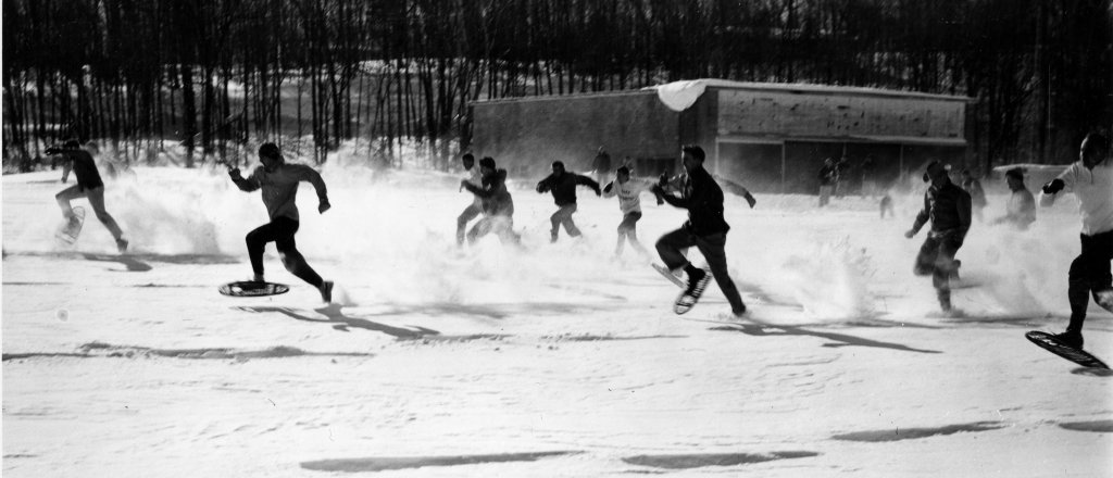 many men running in the snow wearing snowshoes with a forest in the background