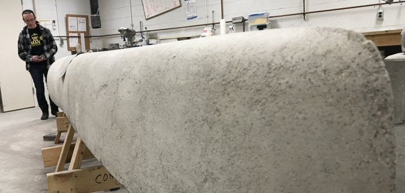 A young woman stands by a concrete molded boat