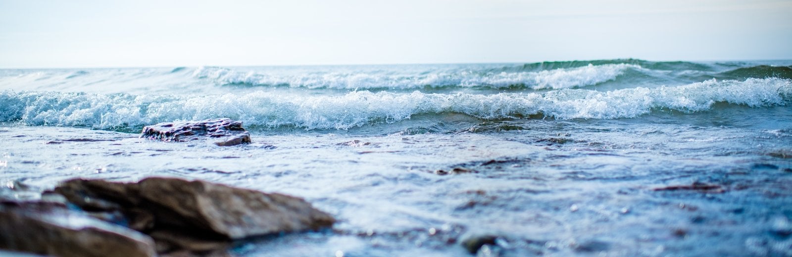 Waves roll toward the shore over several large rocks.