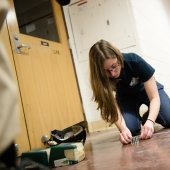 A young woman sets up the screws and bolts on a floor in a hall