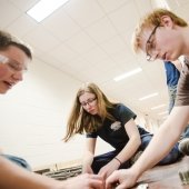 two males and a female set up metal fasteners in a hall