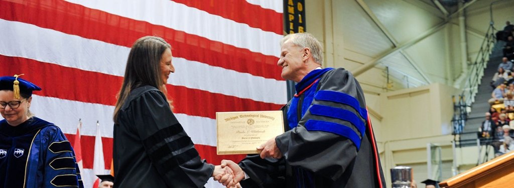 Michigan Tech President Glenn Mroz presents 2017 commencement speaker Paula Wittbrodt '93, with an honorary doctor of philosophy degree.