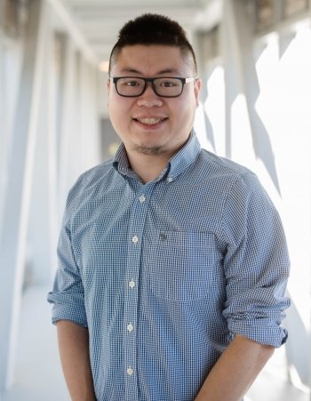 A man poses for a portrait in a hallway.