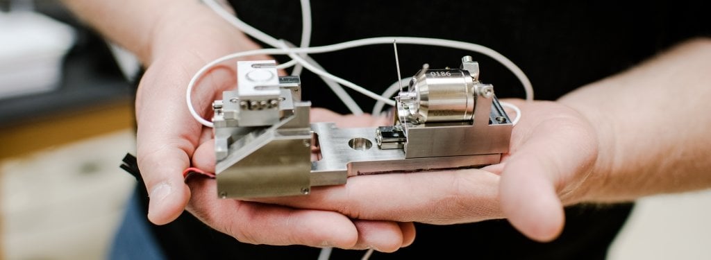 A man holds a diamond-tipped indenter probe instrument.