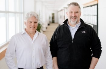 Two men stand in a hallway.