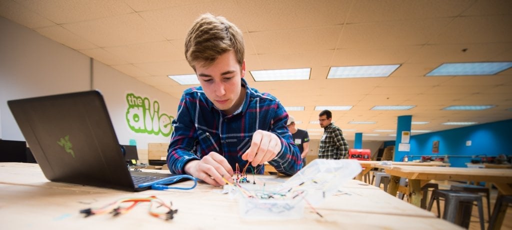 Male student builds with tools and wires in The Alley