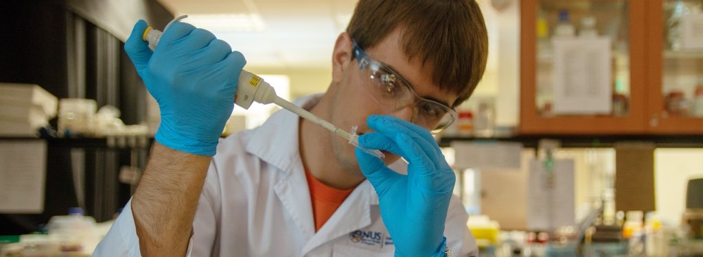 A man pipettes liquid in a lab.