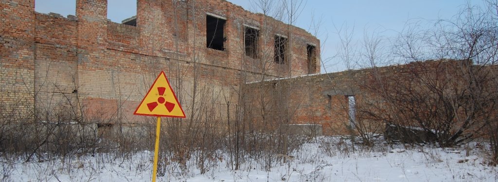 Nuclear radiation sign in front of damaged building.