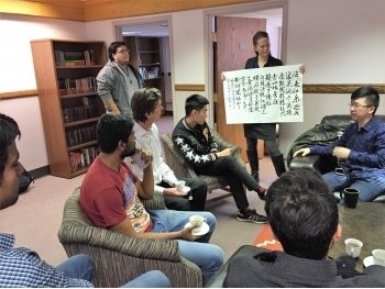 A group of people sitting in chairs with one person standing up inside showing them a map