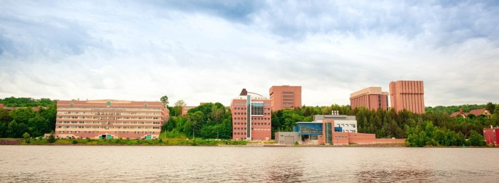 the michigan tech college campus in summer with green trees looking across the water of the portage canal