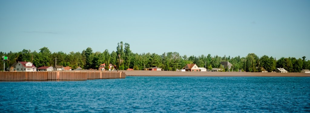 break water at Grand Traverse with stamp sands and town along the forest edge