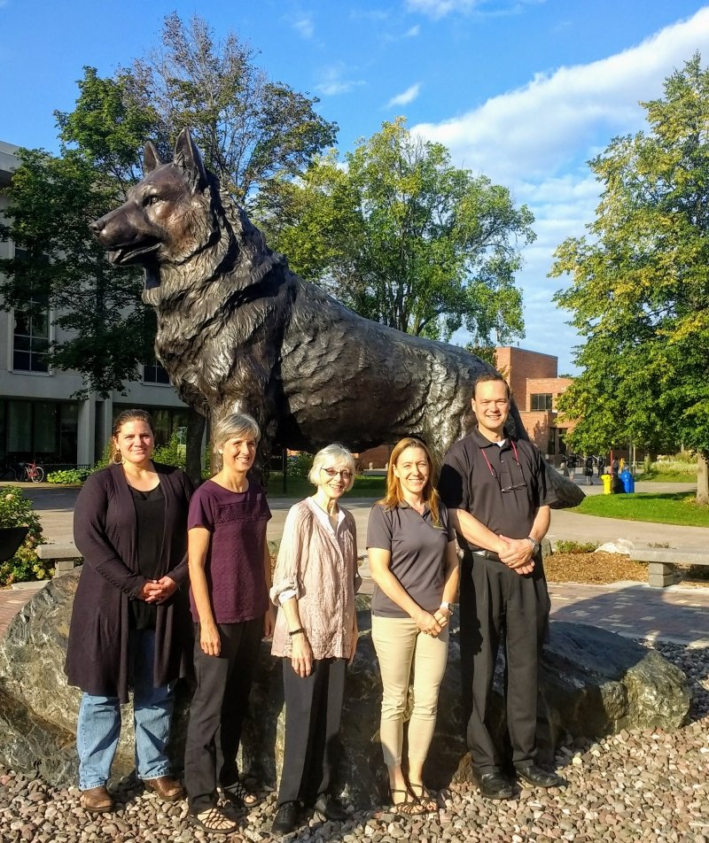 group of people standing in front of the husky statue
