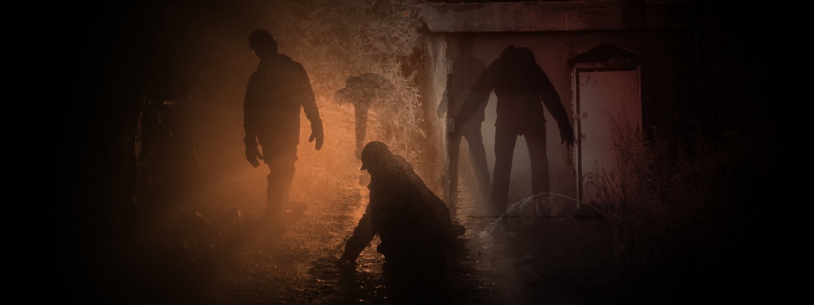 the shadow of zombielike figures wearing hard hats in a hazy red lit dark tunnel underground in a haunted mine.   