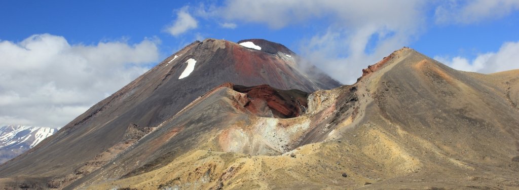 tan and red volcano rising against a blue sky