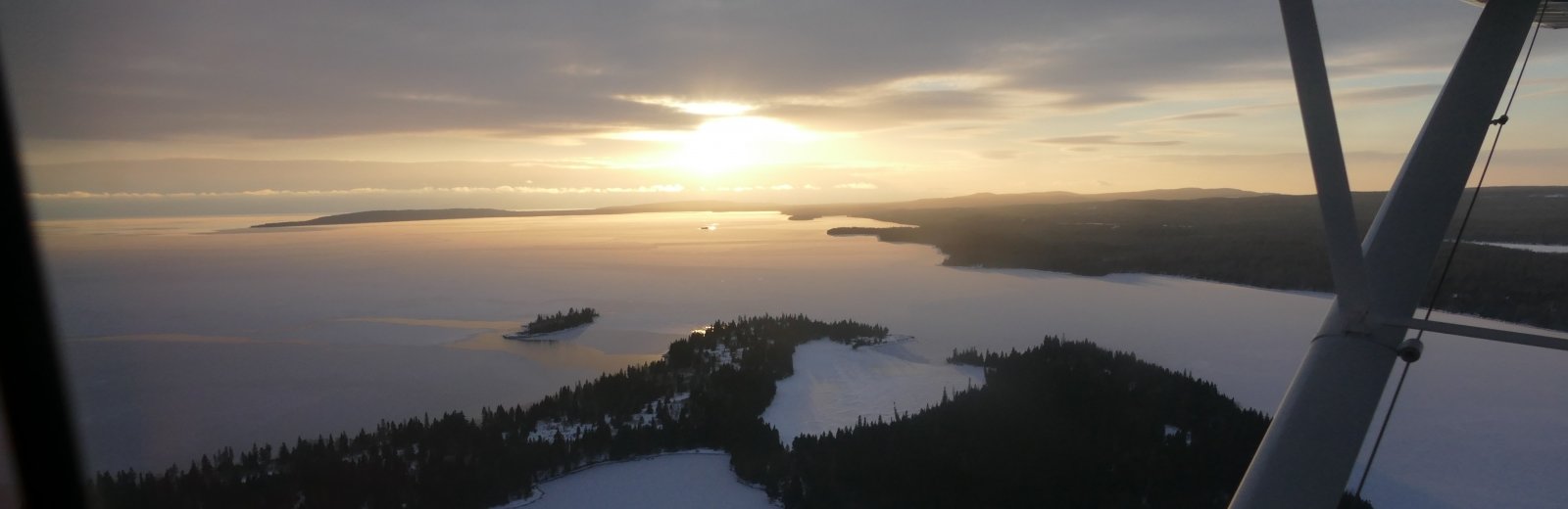 Aerial view from a plane of ridges with trees separated by snow-covered waterways and valleys