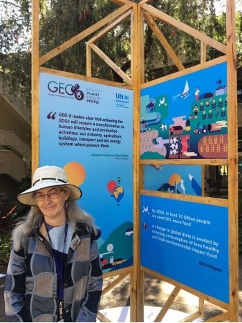 woman in hat standing next to a sign