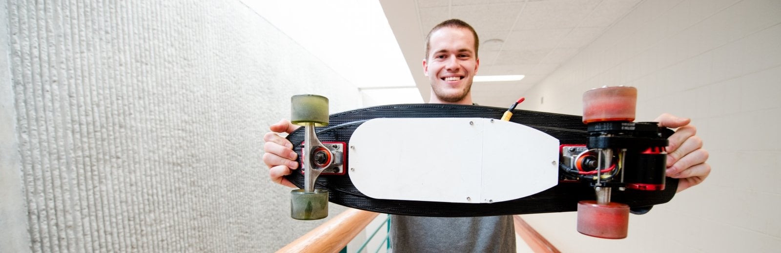 man holding a skateboard, wheels toward the camera