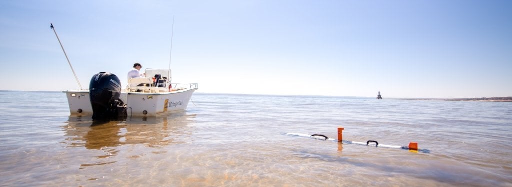 The male occupant of a small Michigan Tech research boat with outboard motor controls the IVER-3 autonomous underwater vehicle near the North Entry light off the coast of the Keweenaw Peninsula in Lake Superior.