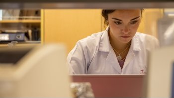 woman sitting at a laptop in a lab coat