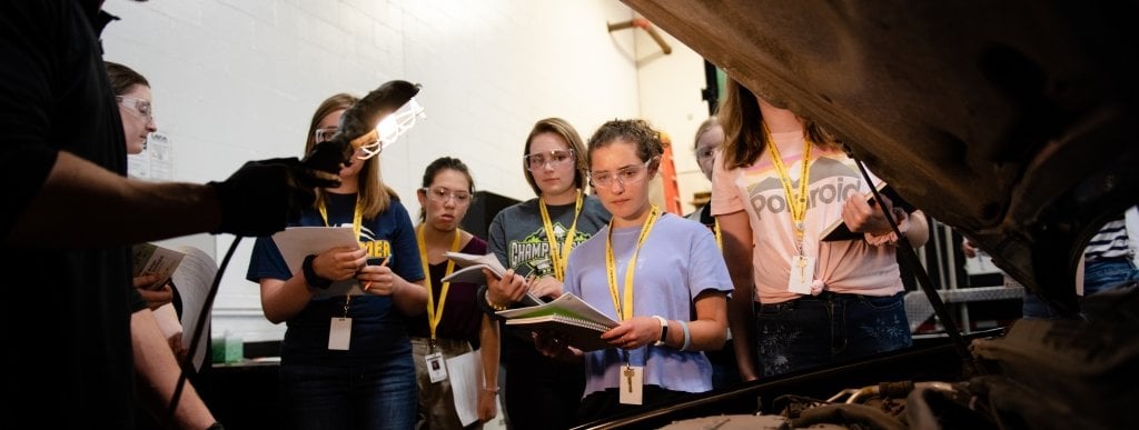 Students in the Women in Automotive Engineering program investigate engineering careers in the automotive industry, including mechanical and electrical aspects. Credit: Peter Zhu group of young woman next to a car with the hood up