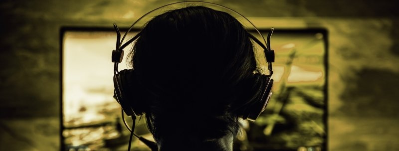 A woman wearing a headset plays a computer-based video game