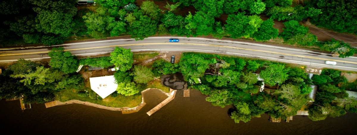 Roads are the lifeblood of modern society and upkeep is no easy feat. drone image overhead of road with blue car and trees