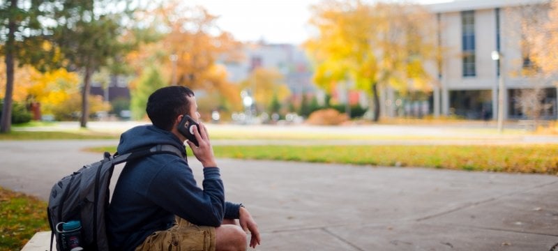 student using a cell phone sitting on a picnic table