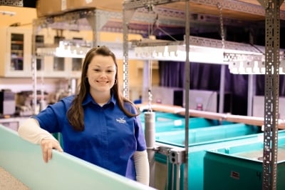 A portrait of Lauren Jescovitch in a room with holding tanks for fish.