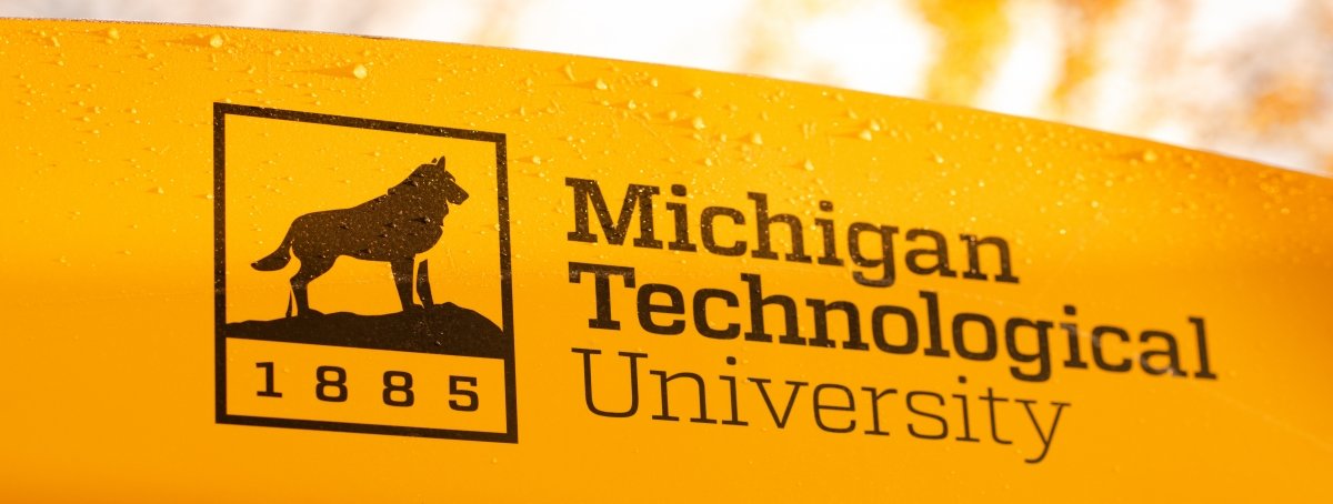 Michigan Technological University sign with 1885, dog on rock, and melty snowflakes