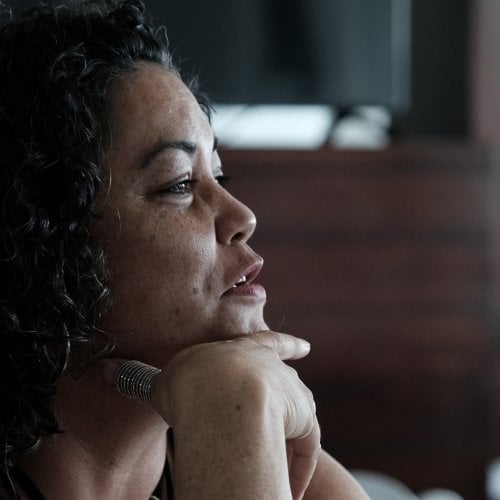 Side profile of a woman with hand under her chin holding a pen intently concentrating